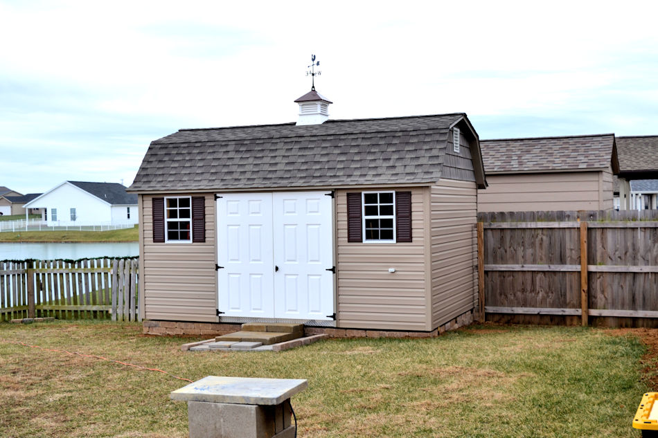 lofted garden shed with tan siding, white double doors, and cupola