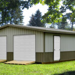 two car garage with gray and brown siding, ramps, and two side doors