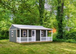 she shed with green siding, front porch white white vinyl railings, and metal roof