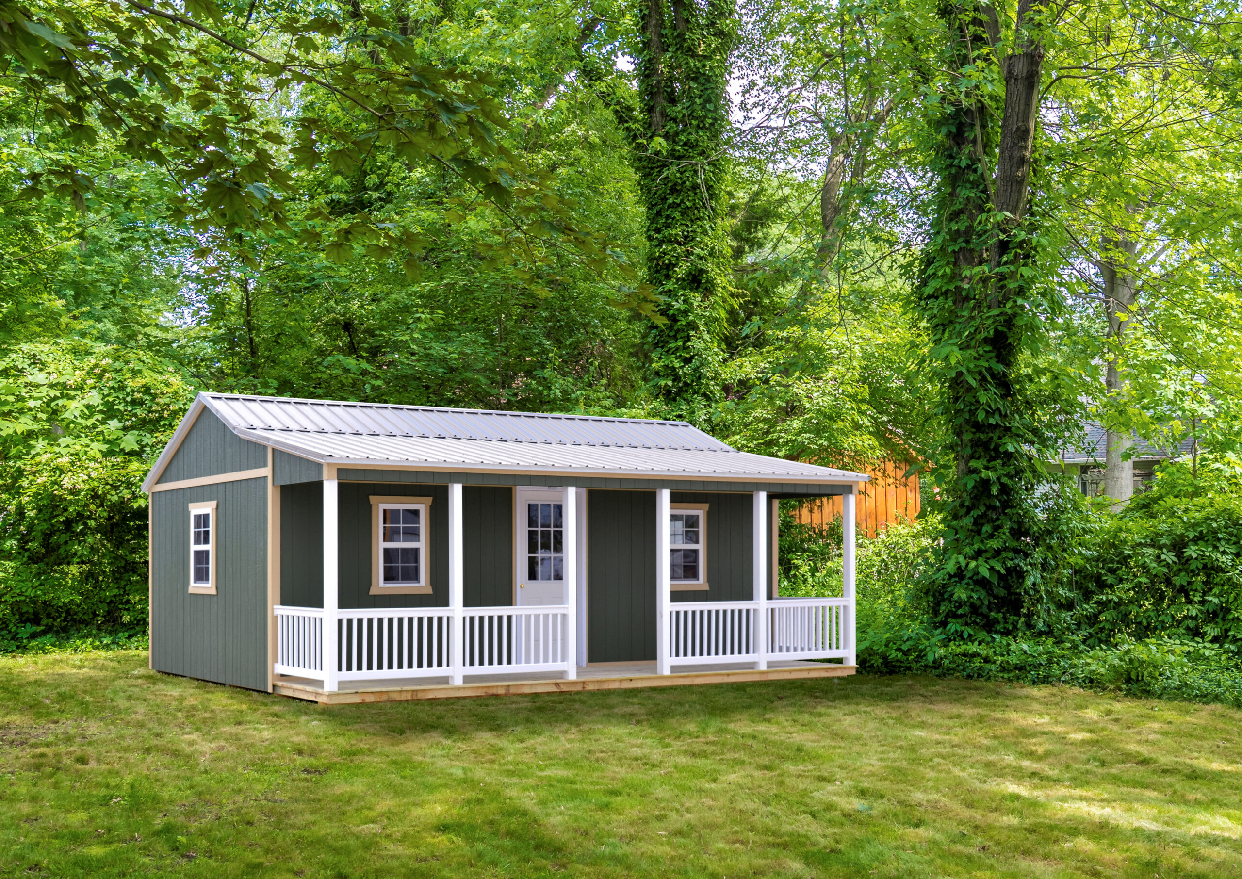 she shed with green siding, front porch white white vinyl railings, and metal roof