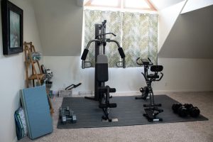 Home gym set up with a weight system, dumbbells, and a stationary bike.