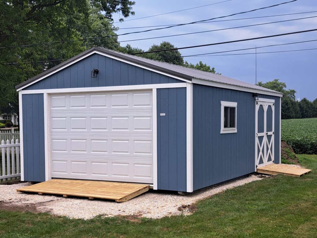 one car garage with blue siding, white trim and doors, and ramp