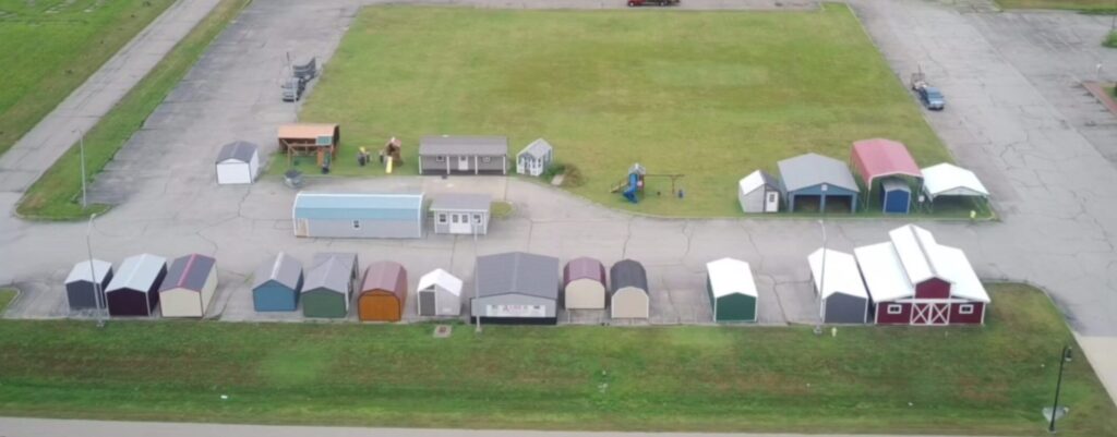 Drone overhead view of Raber's Seymour lot with an assortment of sheds, garages, carports, barns, playhouses, and playgrounds.