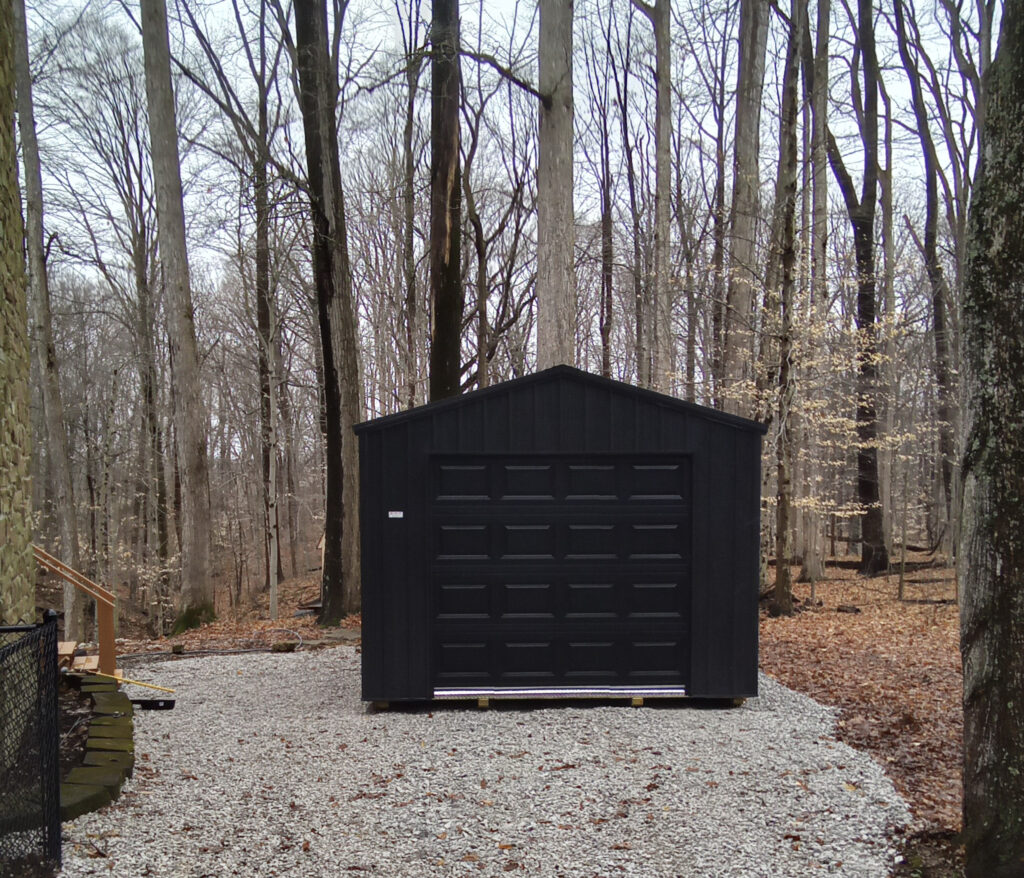 detached garage with black siding and black door 