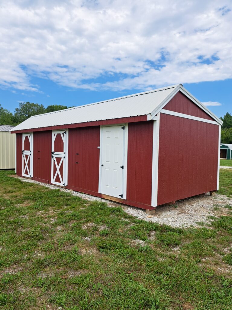 wooden horse barn with red siding and white trim, doors, and roof