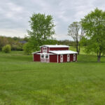 monitor horse barn with red siding on a pasture