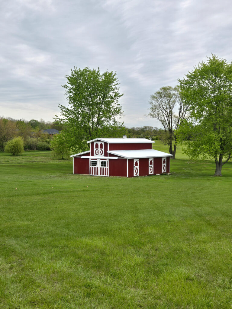 monitor horse barn with red siding on a pasture