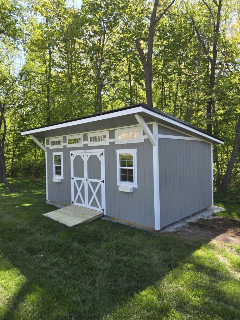 classic studio shed with gray siding and transom windows