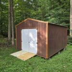 metal utility shed with brown siding and wood ramp