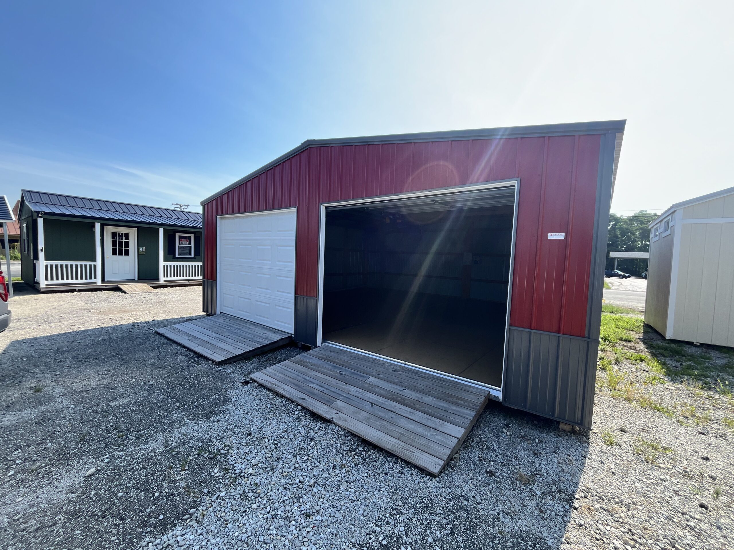24x24 two-car garage with red metal siding, dark gray wainscot, 2 white garage doors, and 2 ramps.