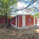 two car garage with red metal siding and white trim